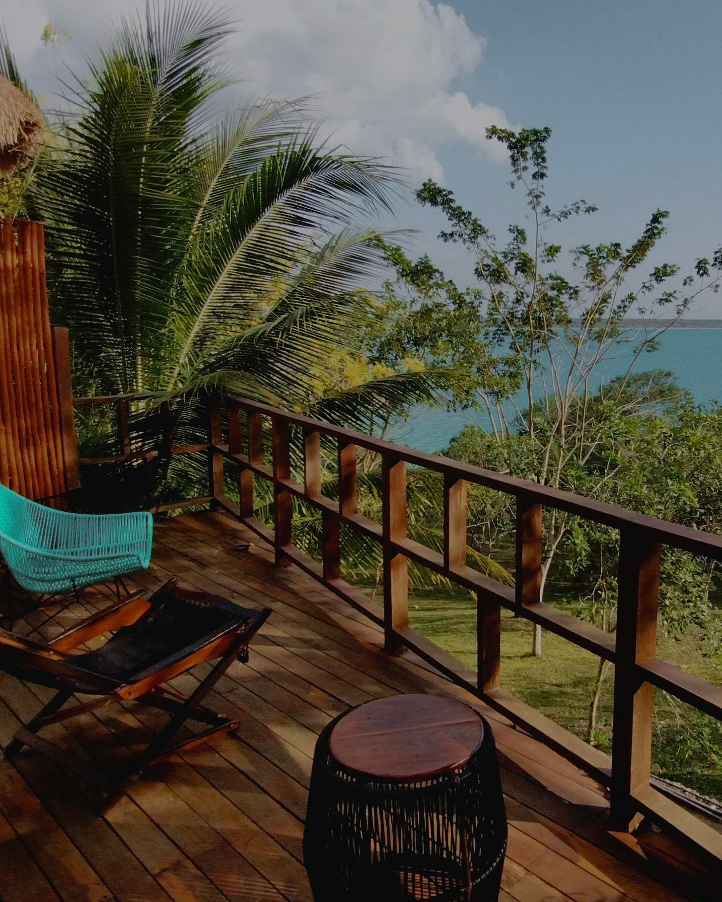Una terraza de madera con sillas y una mesa con vista al mar.