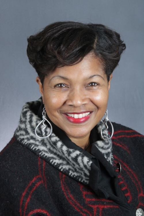 A dining room with a table and chairs and a wooden staircase.