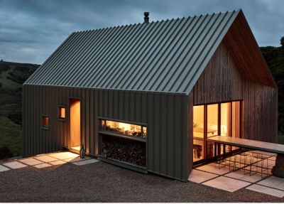 A small house with a metal roof is lit up at night