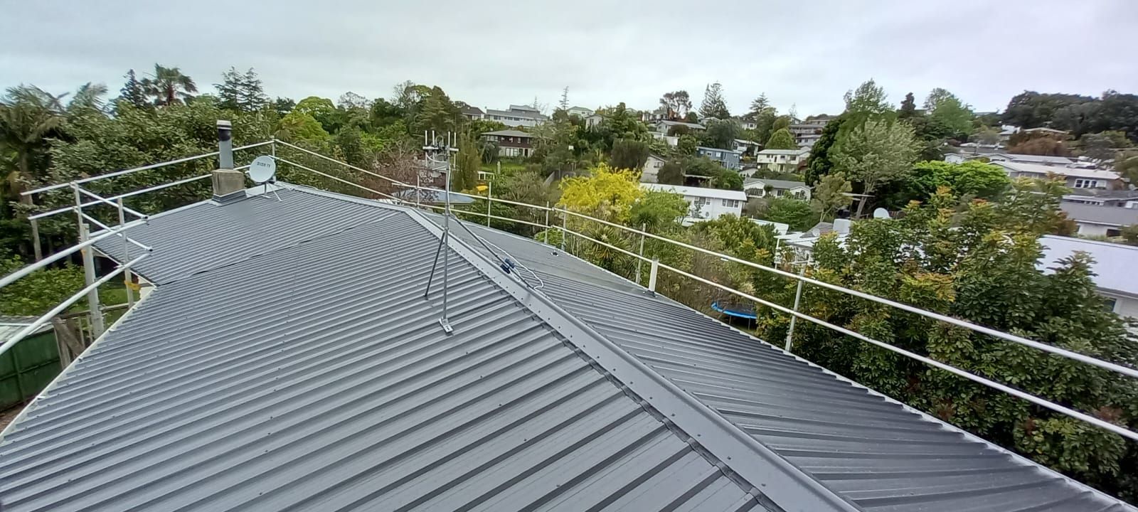 A roof with a rope fence around it and trees in the background.