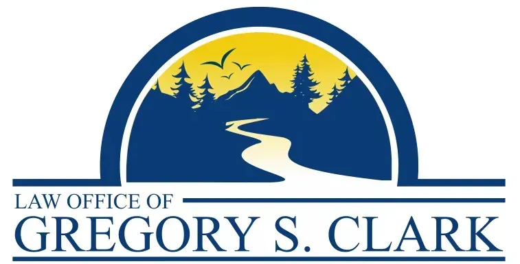 Law Office of Gregory S. Clark logo: mountain scene with river, trees, birds, and yellow sky, enclosed by a blue arch.