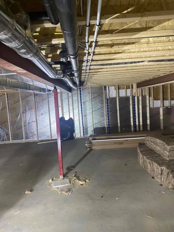 A basement under construction with pipes hanging from the ceiling.
