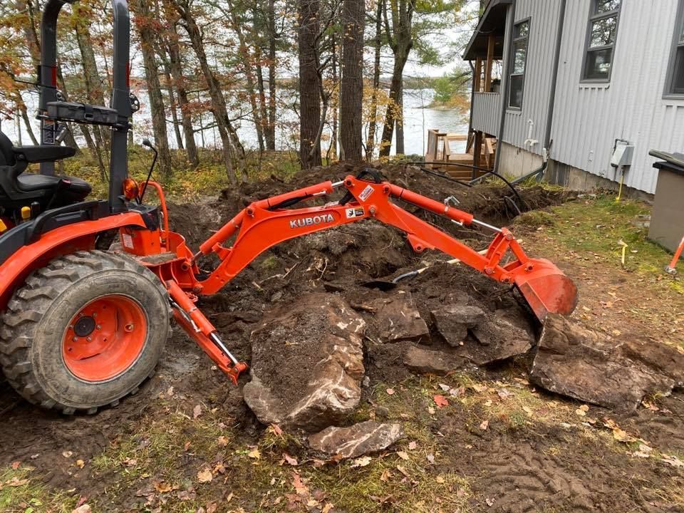 A tractor is digging a hole in the ground in front of a house.