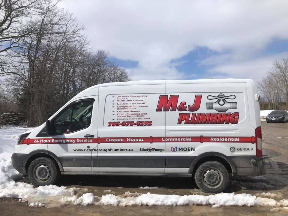 A m & j plumbing van is parked in the snow.