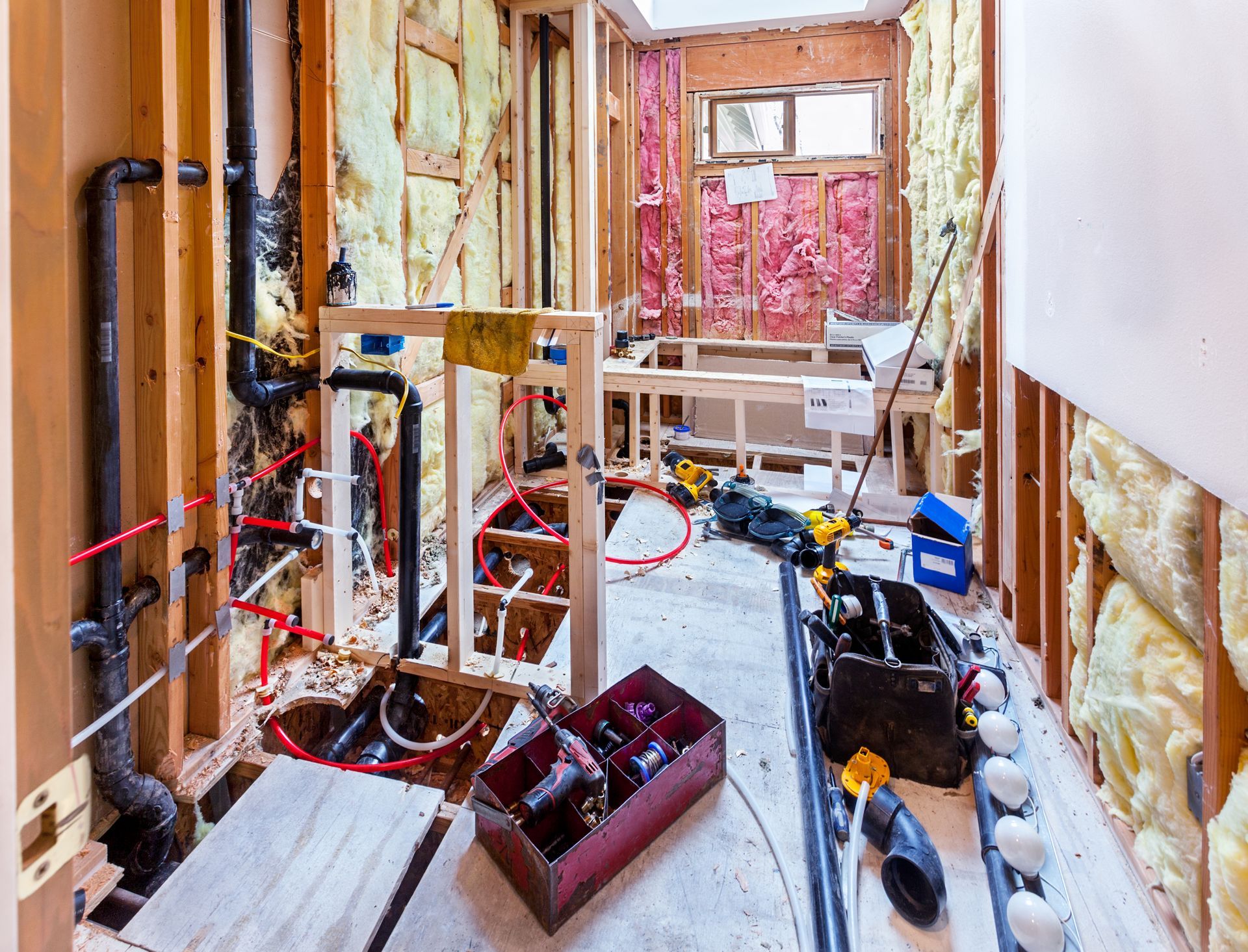 A bathroom under construction with tools and pipes on the floor.