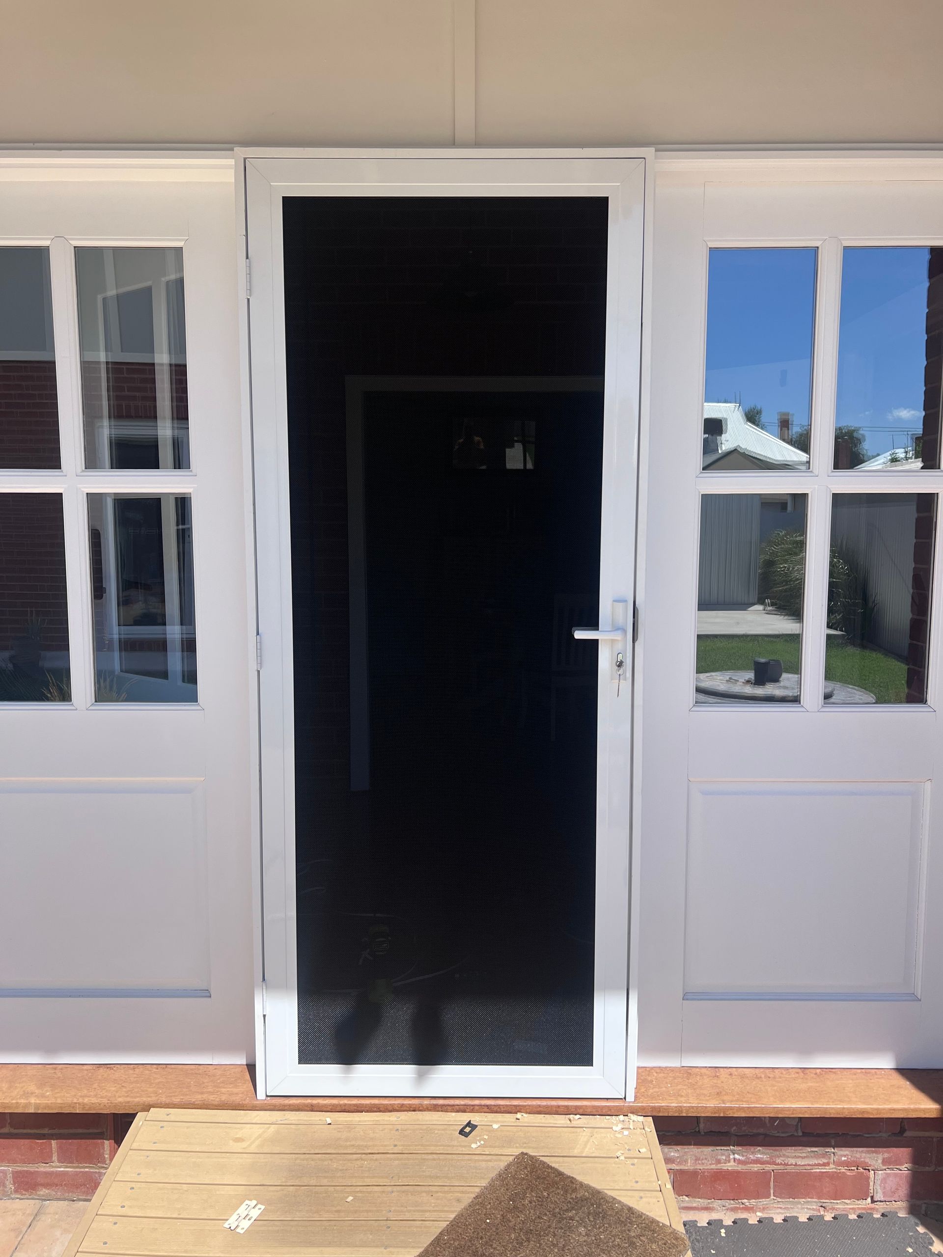 A White Wall Featuring A Screen Door With A Rug Placed In Front Of It — SG Glass & Aluminium in Wagga Wagga, NSW