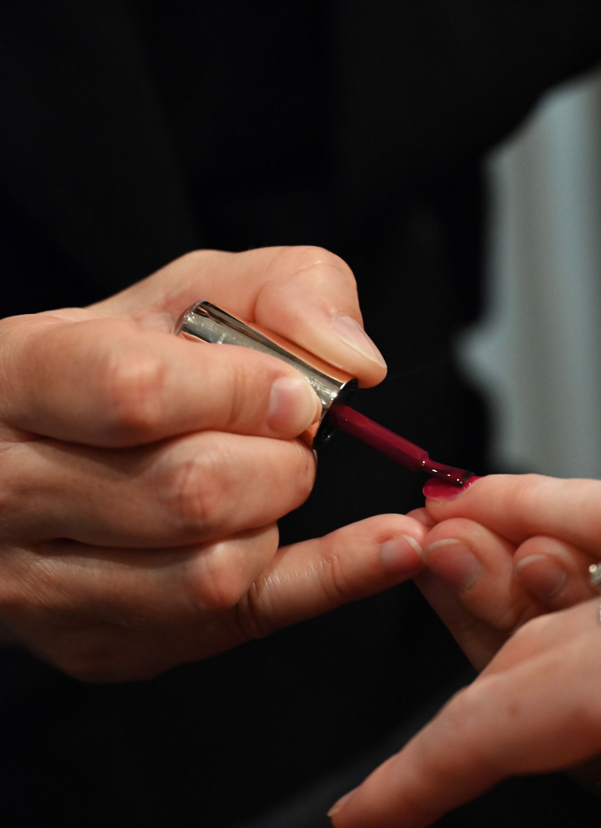 Une personne applique du vernis à ongles sur les ongles d'une autre personne