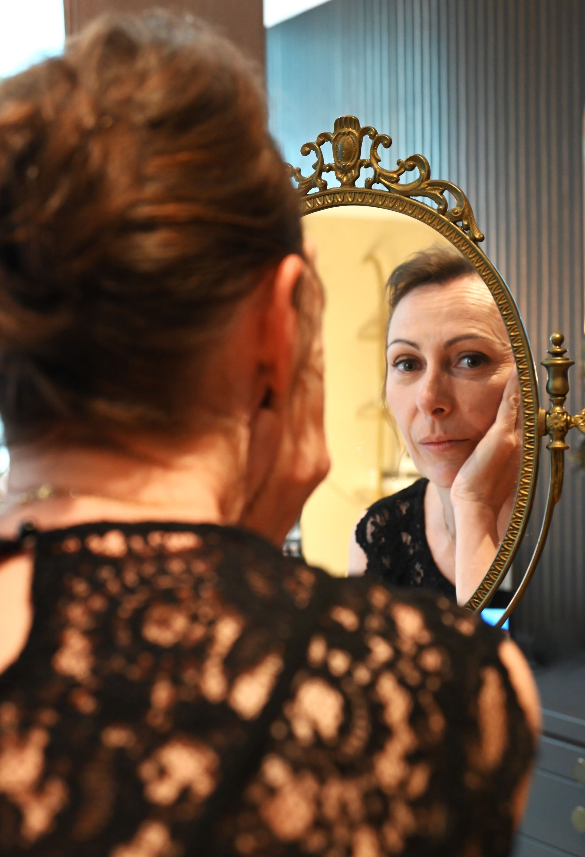 Une femme porte un haut en dentelle noire et un collier en or