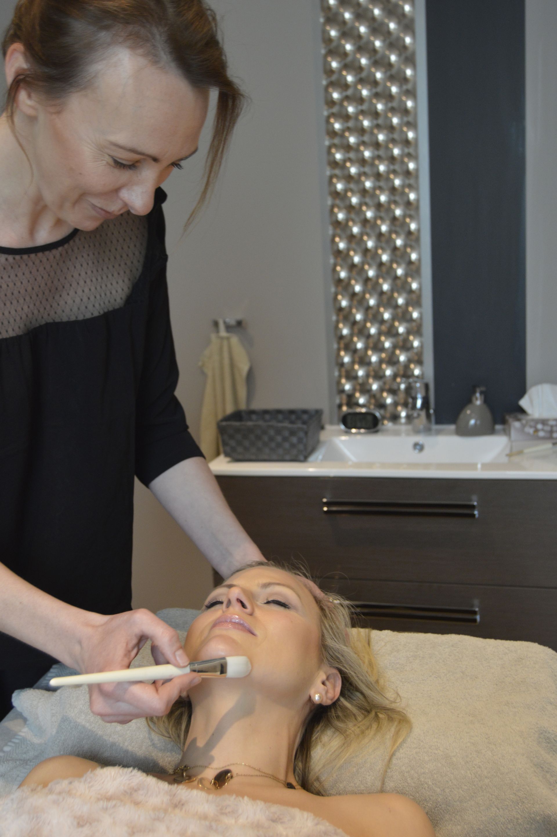 Une femme reçoit un soin du visage dans un spa.