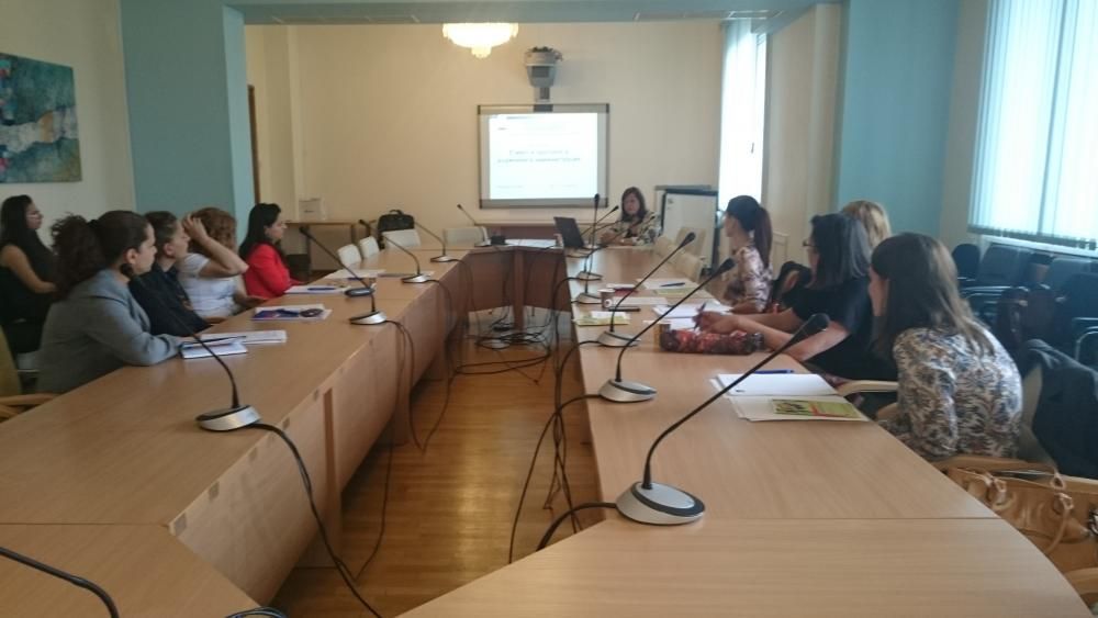 Un grupo de personas está sentado en mesas largas en una sala de conferencias.