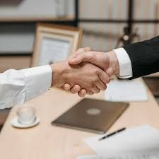 Un hombre y una mujer se dan la mano sobre una mesa.