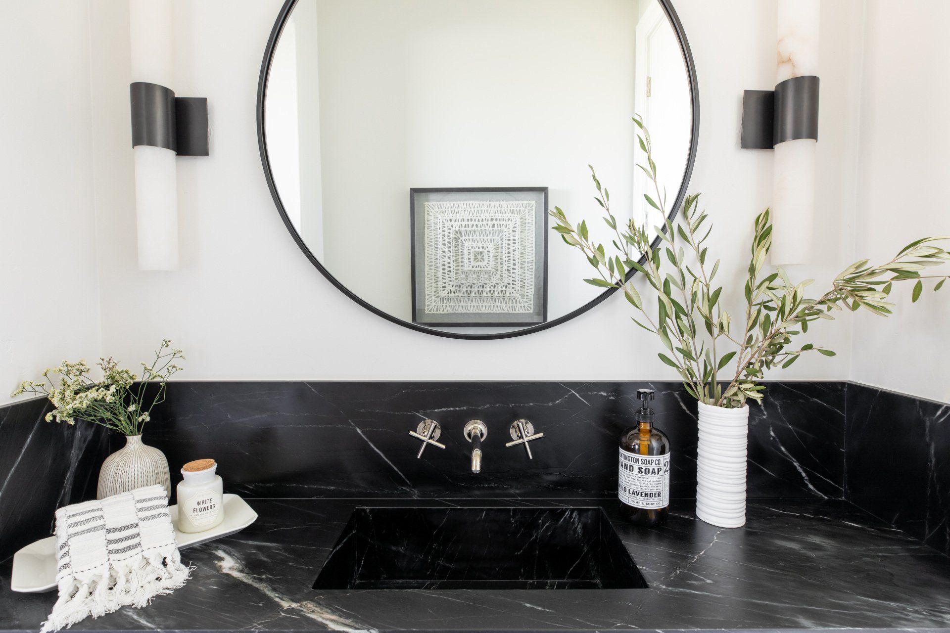 A bathroom with a black sink and a round mirror.