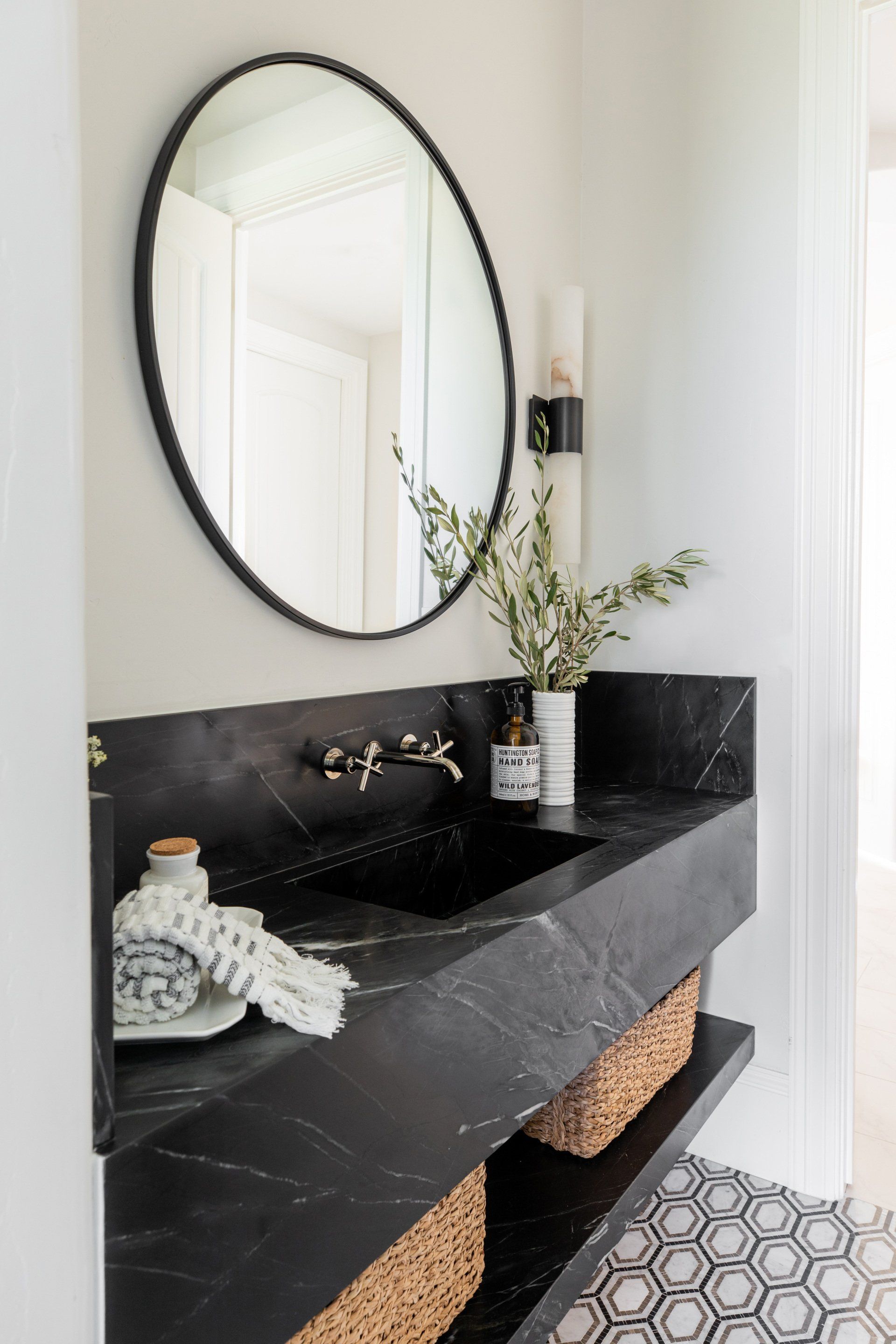 A bathroom with a black sink and a round mirror.