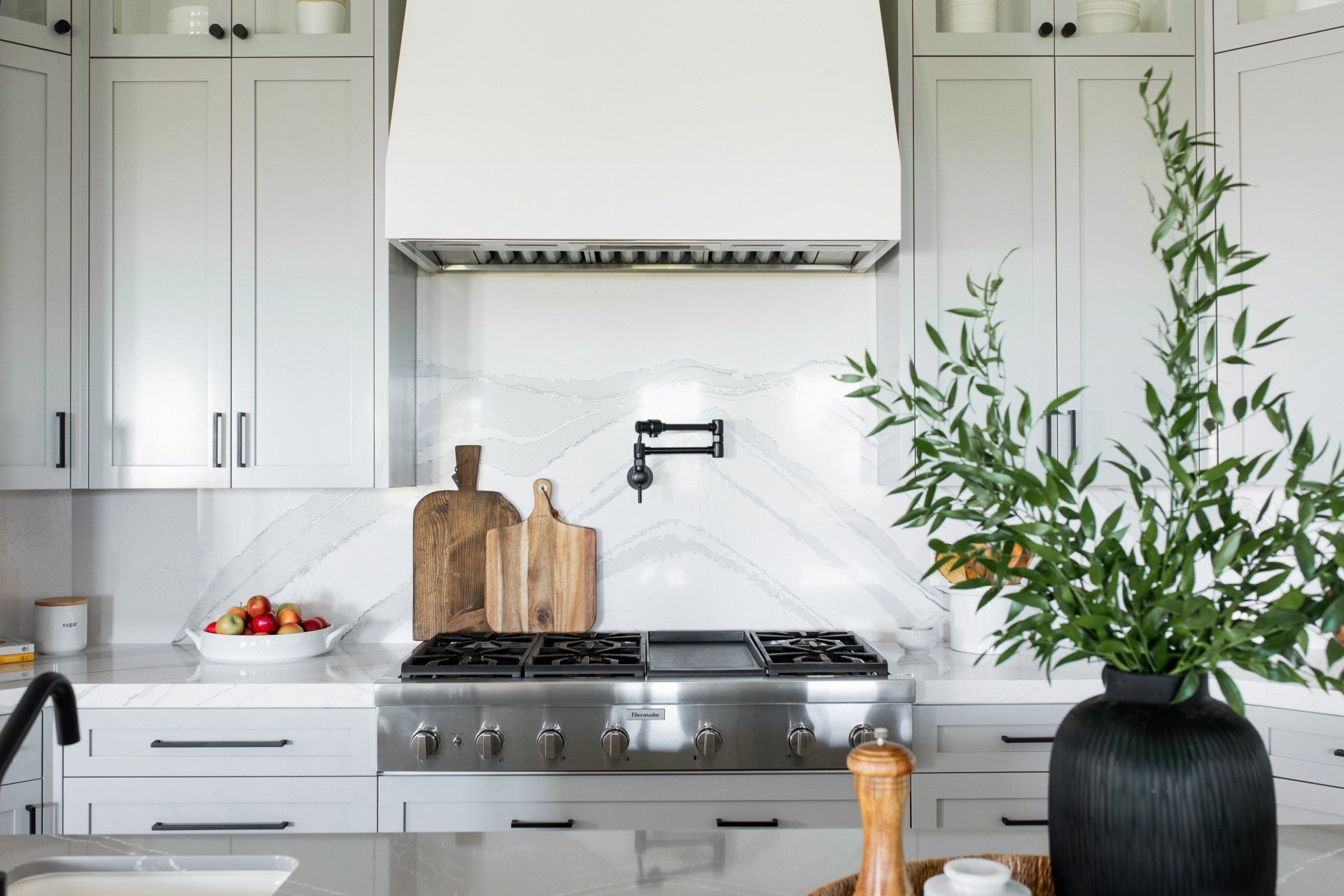 A kitchen with white cabinets and a stove top oven.