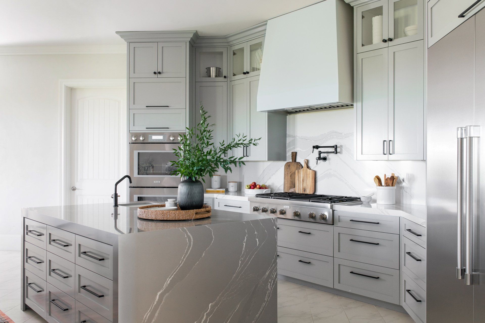 A kitchen with white cabinets , stainless steel appliances , and a large island.