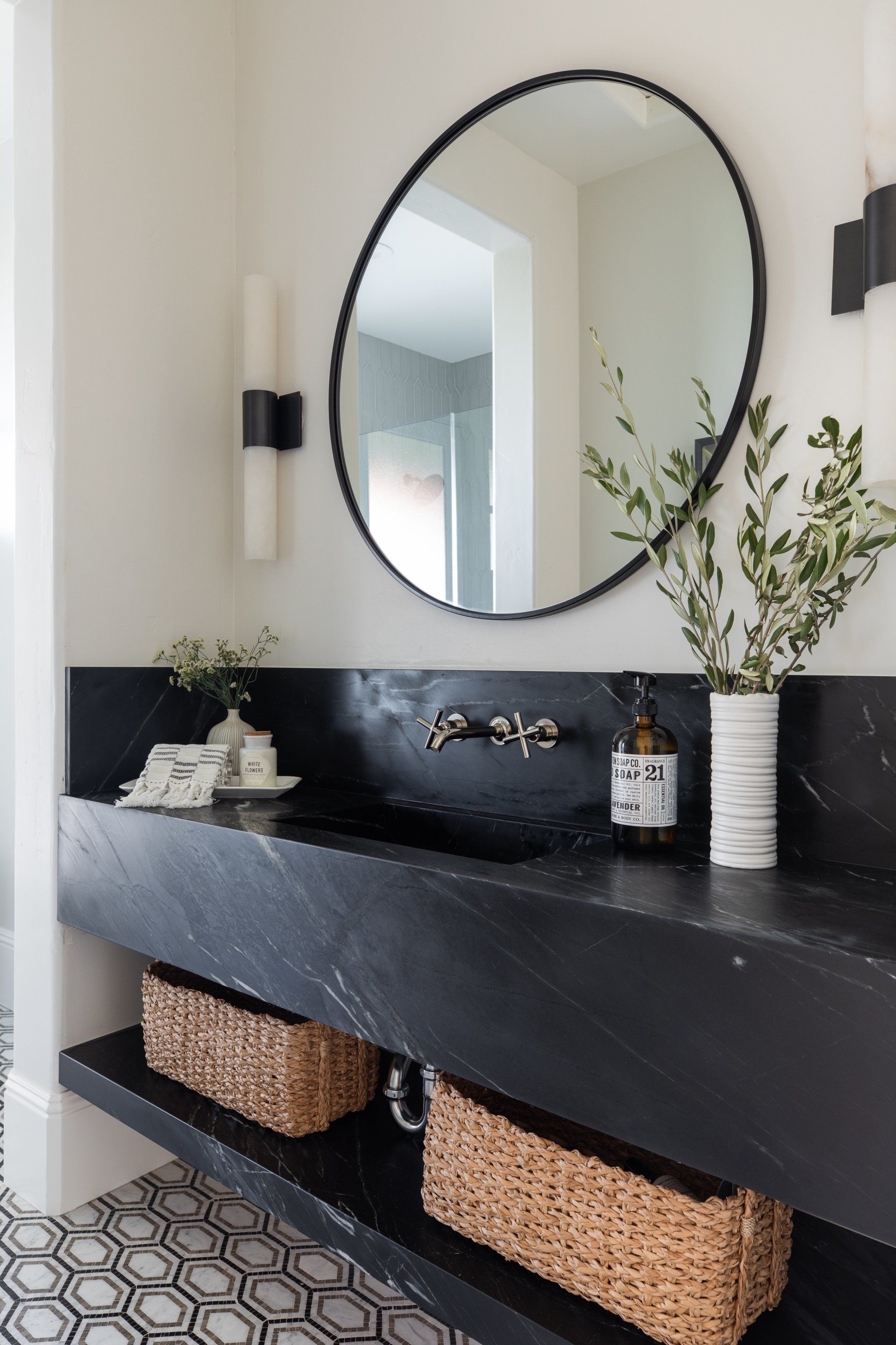 A bathroom with a black sink and a round mirror.