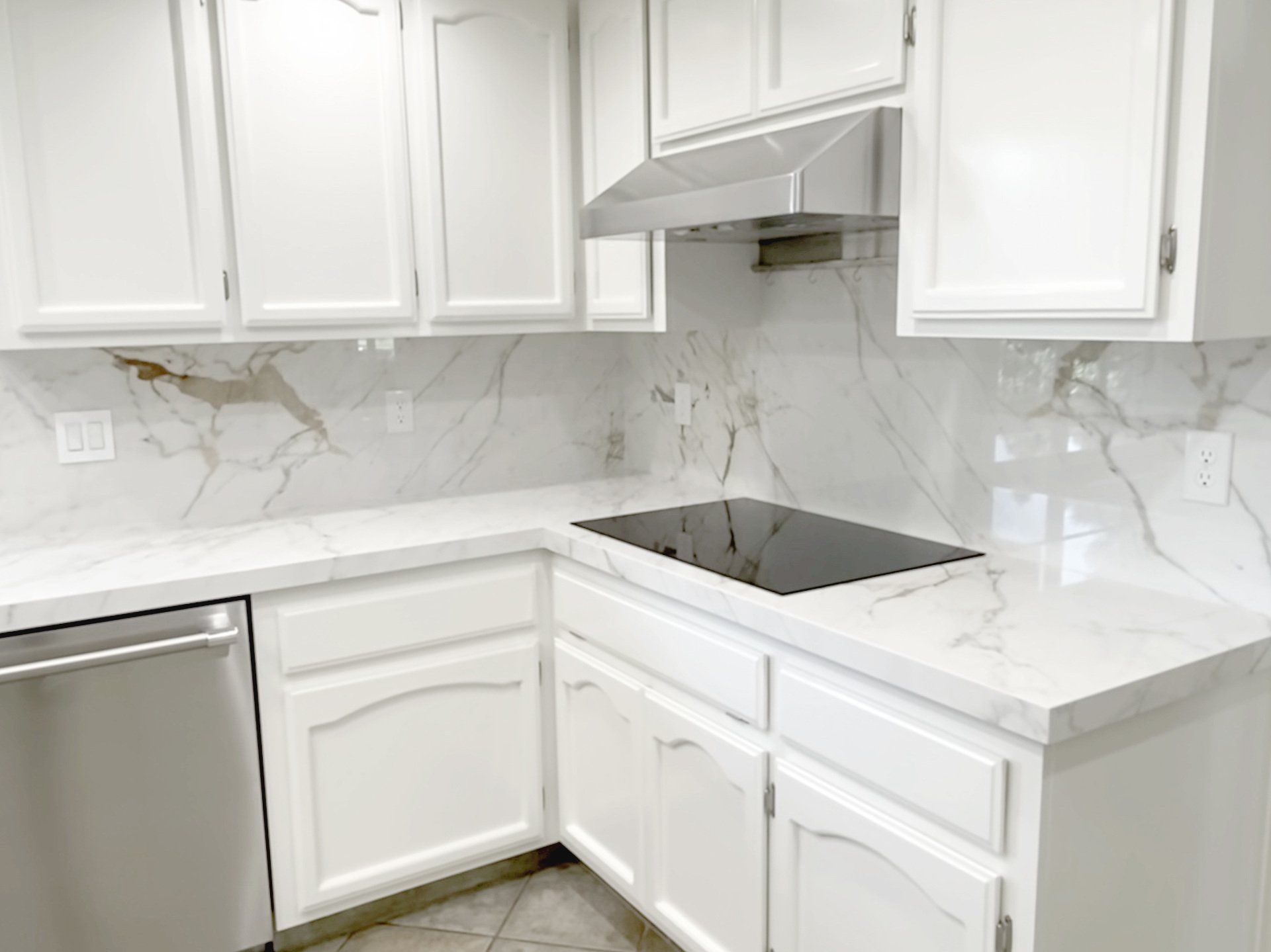 A kitchen with white cabinets , stainless steel appliances , and a stove top oven.