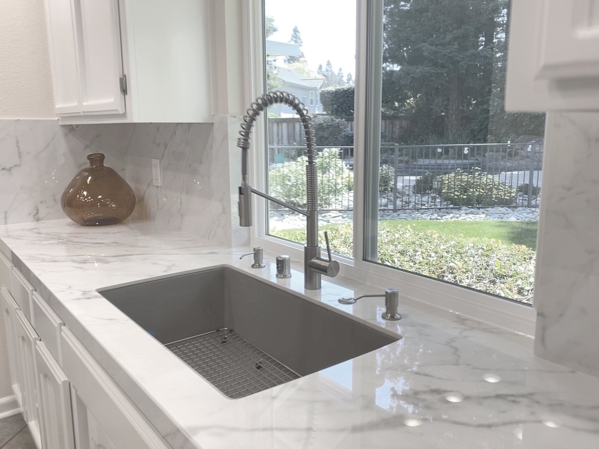 A kitchen sink with a faucet and a window.