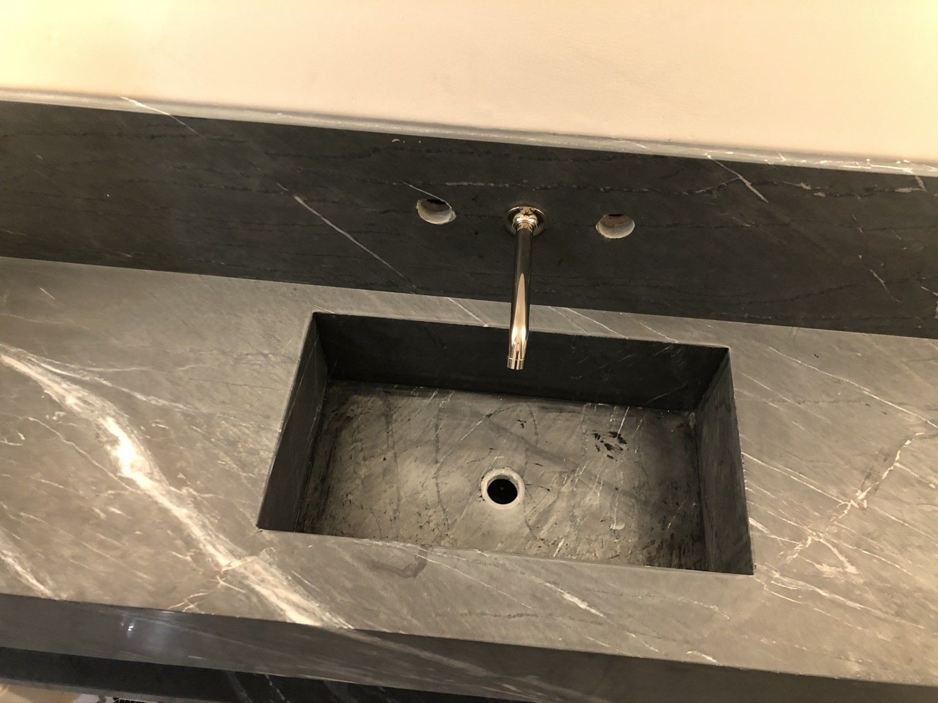 A bathroom sink with a faucet and a black counter top.