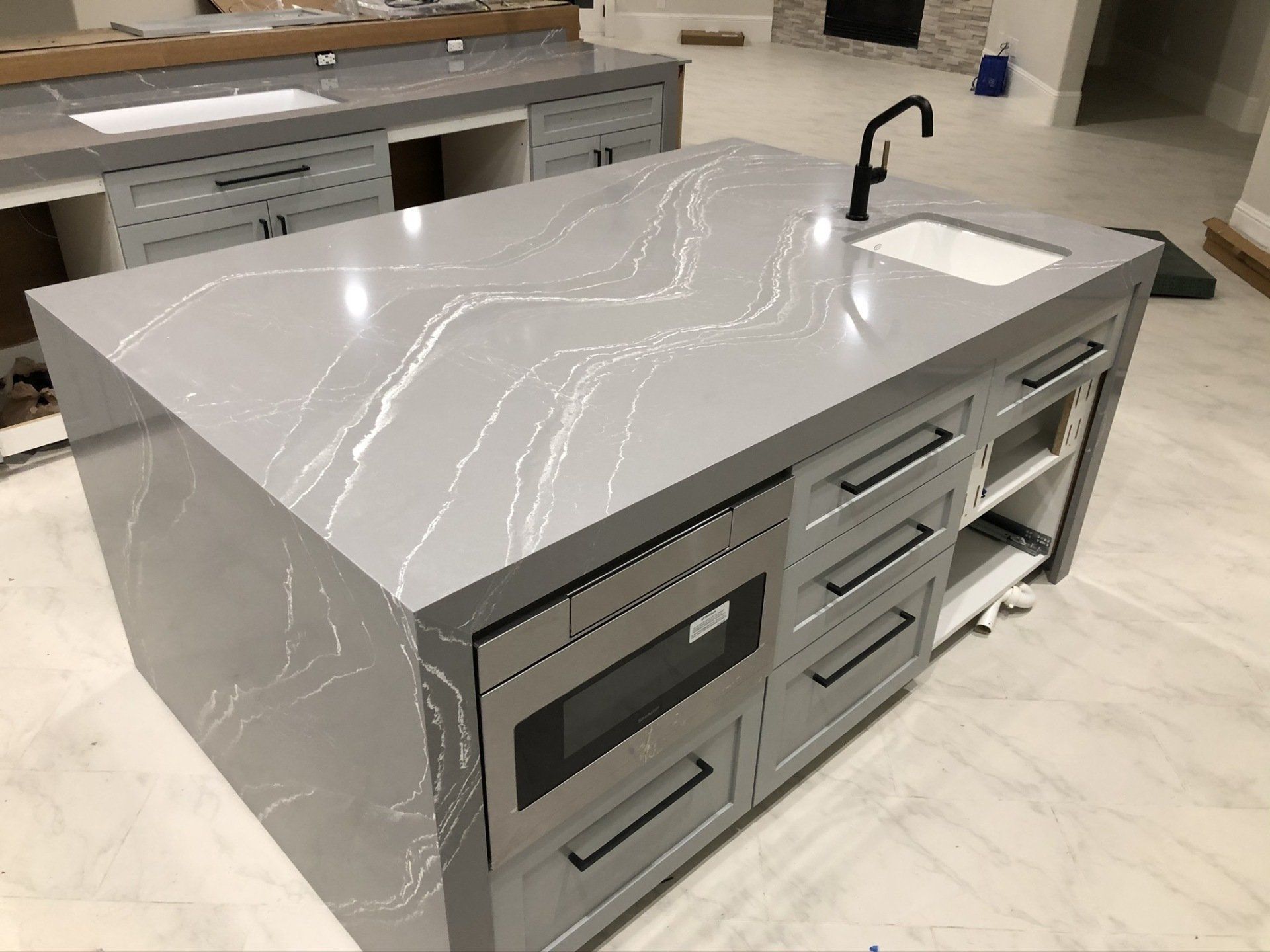 A kitchen island with a sink , microwave , and drawers.