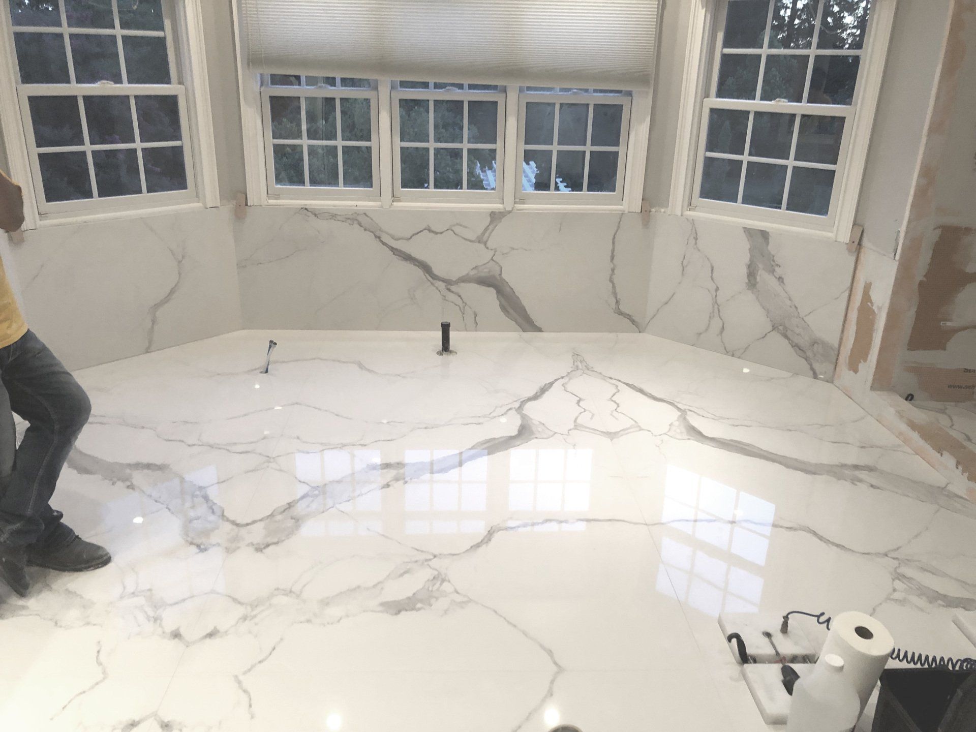 A man is standing on a marble floor in a room with windows.