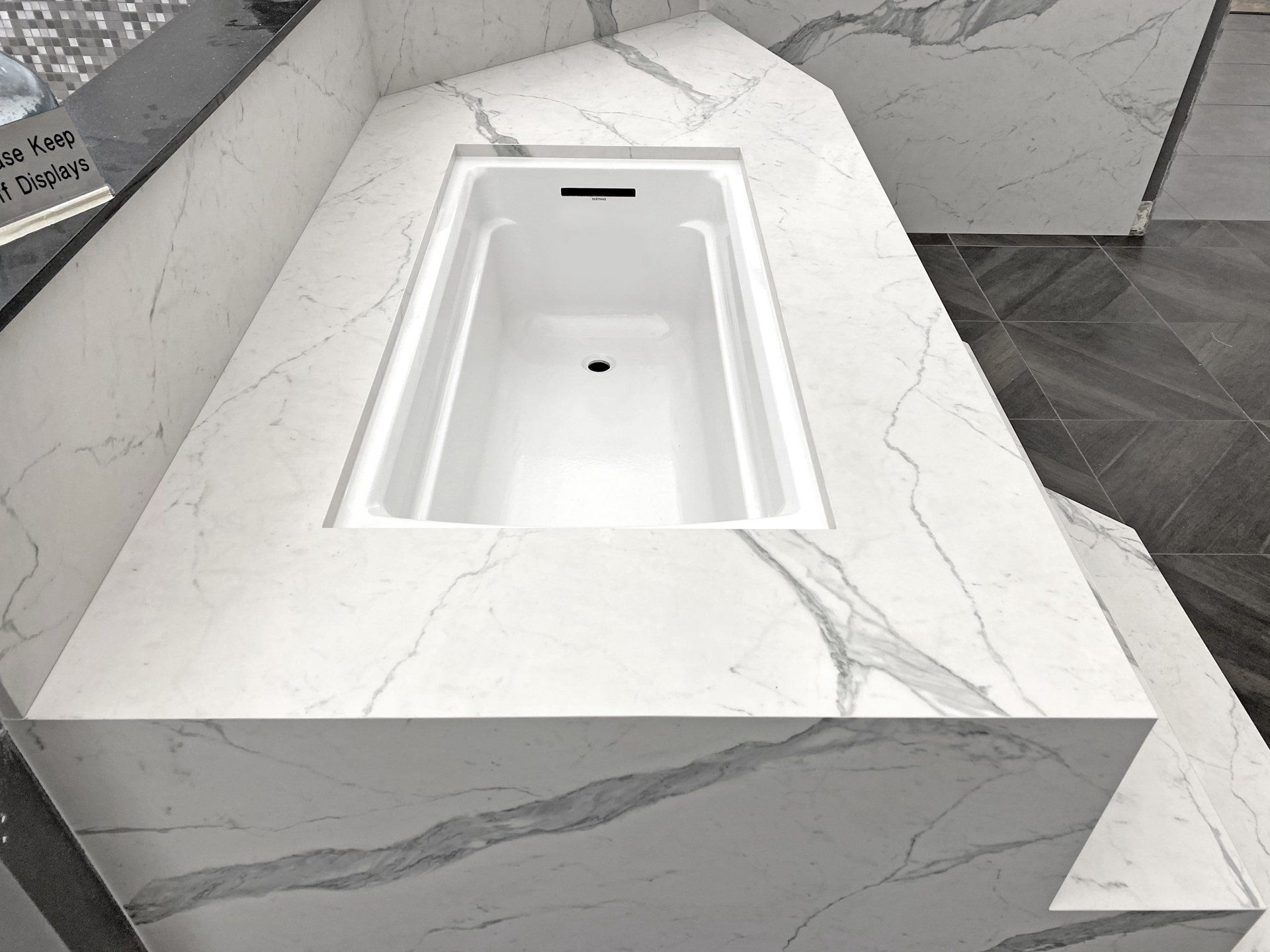 A bathtub is sitting on top of a marble counter in a bathroom.
