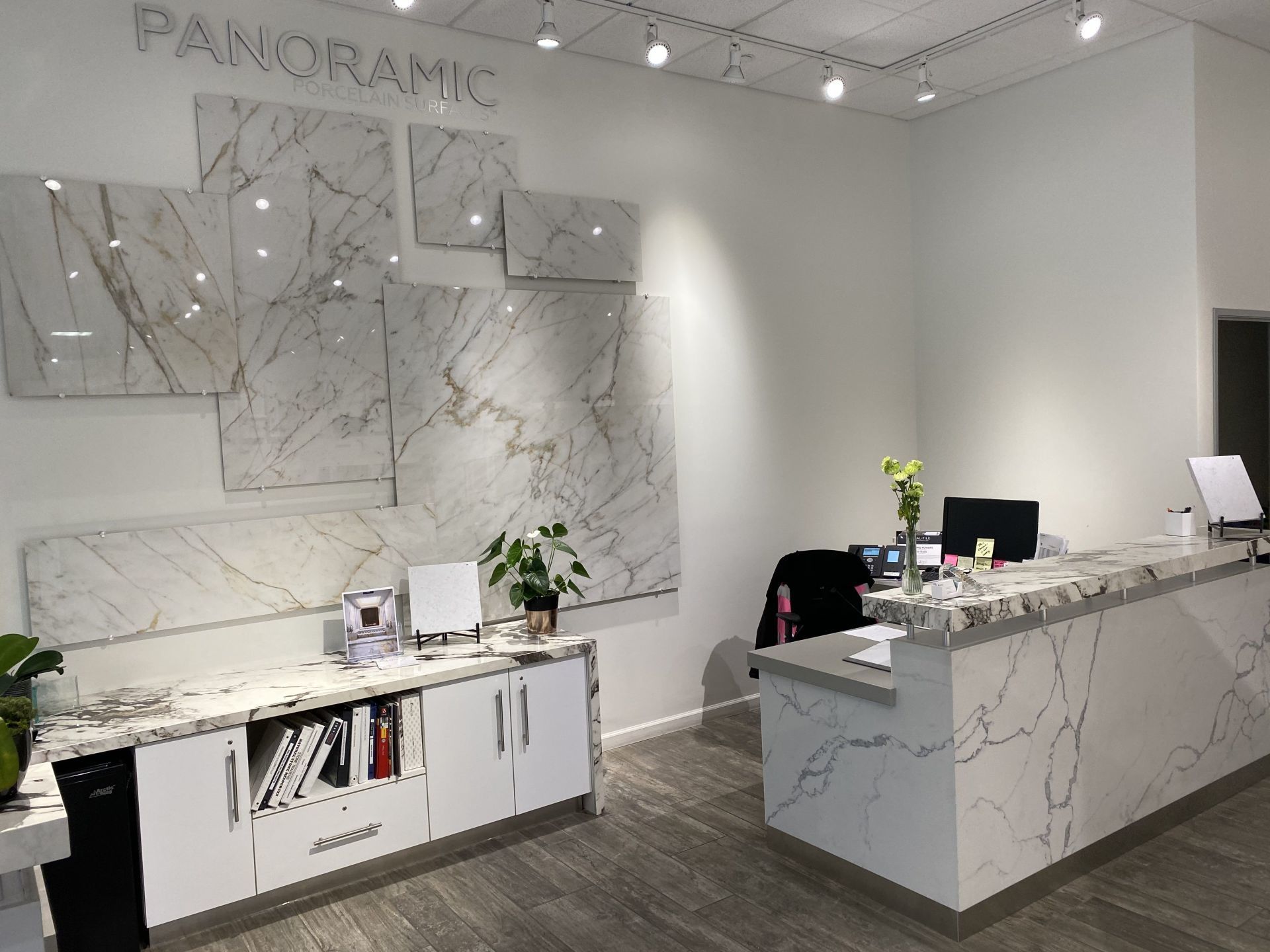 A large white counter in a room with a marble wall behind it.