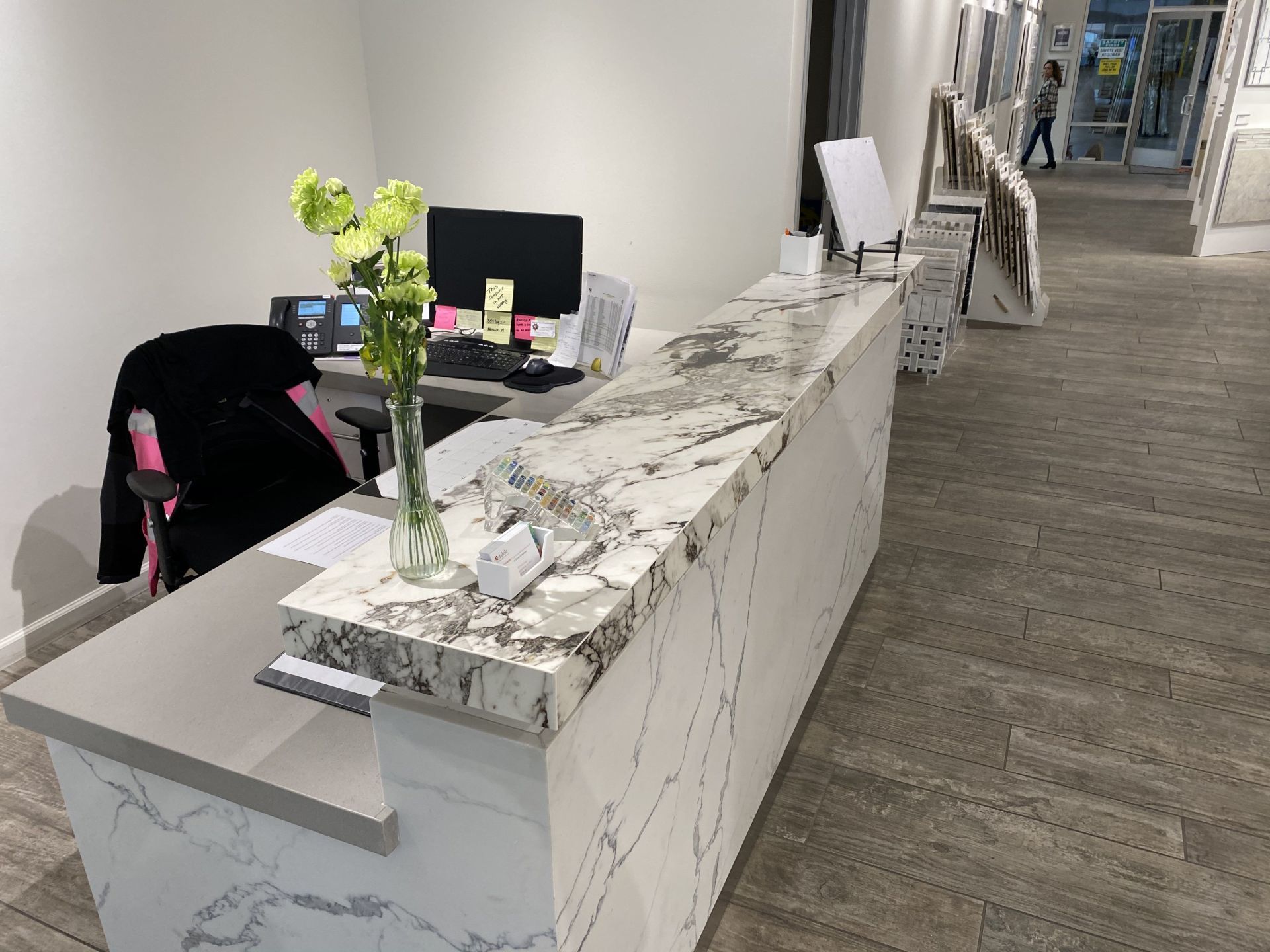 A long white marble counter with a vase of flowers on it.
