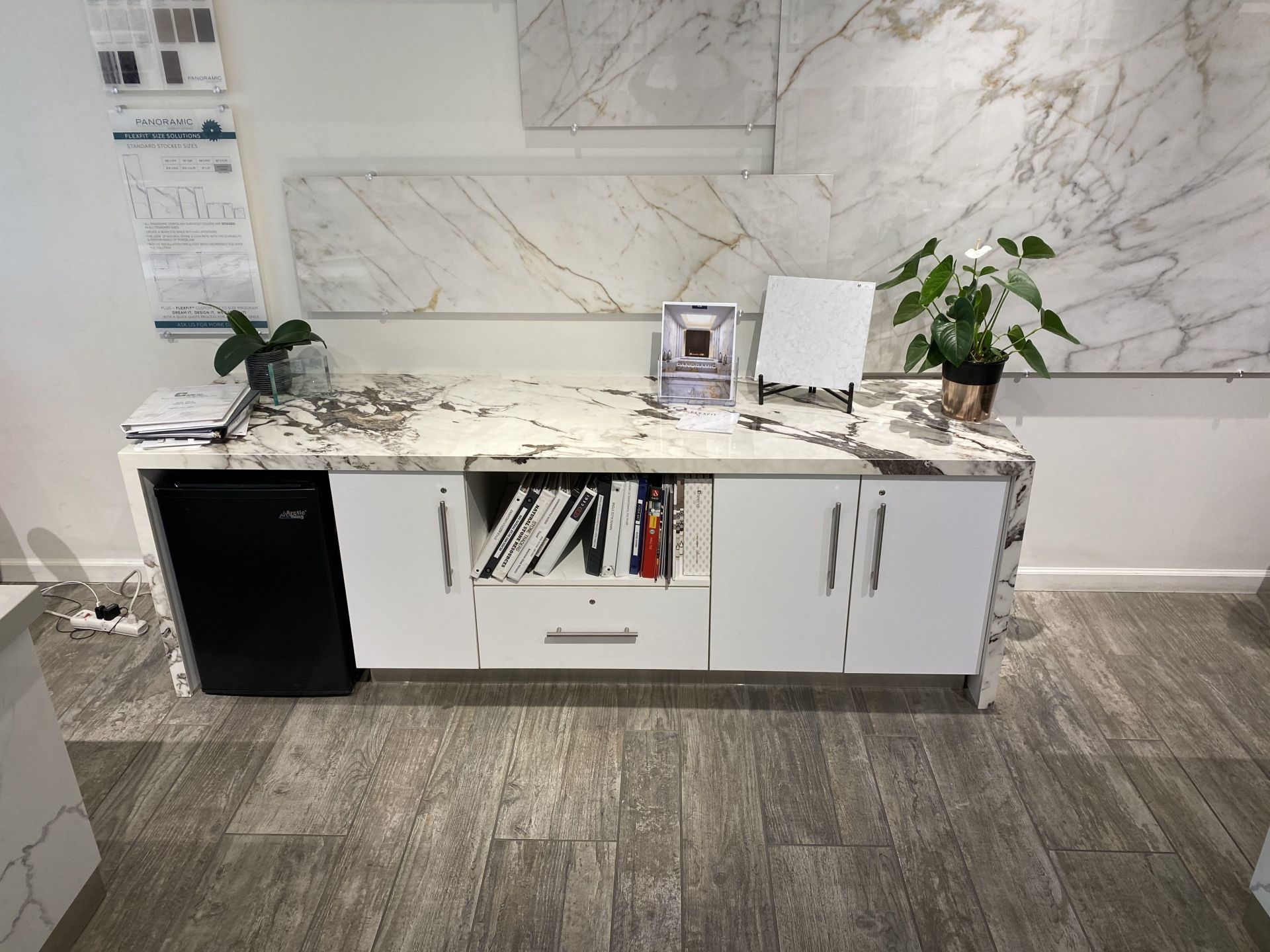 A kitchen with a marble counter top and white cabinets