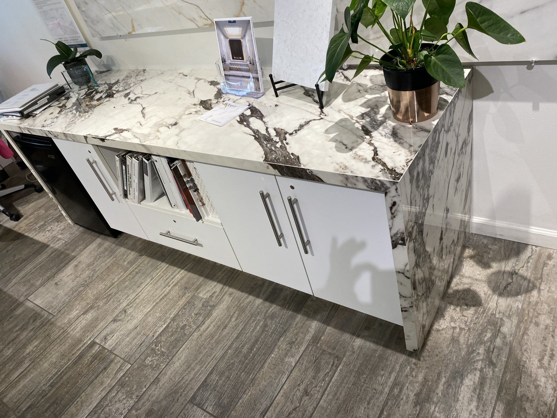 A marble counter top with white cabinets and a plant on top.