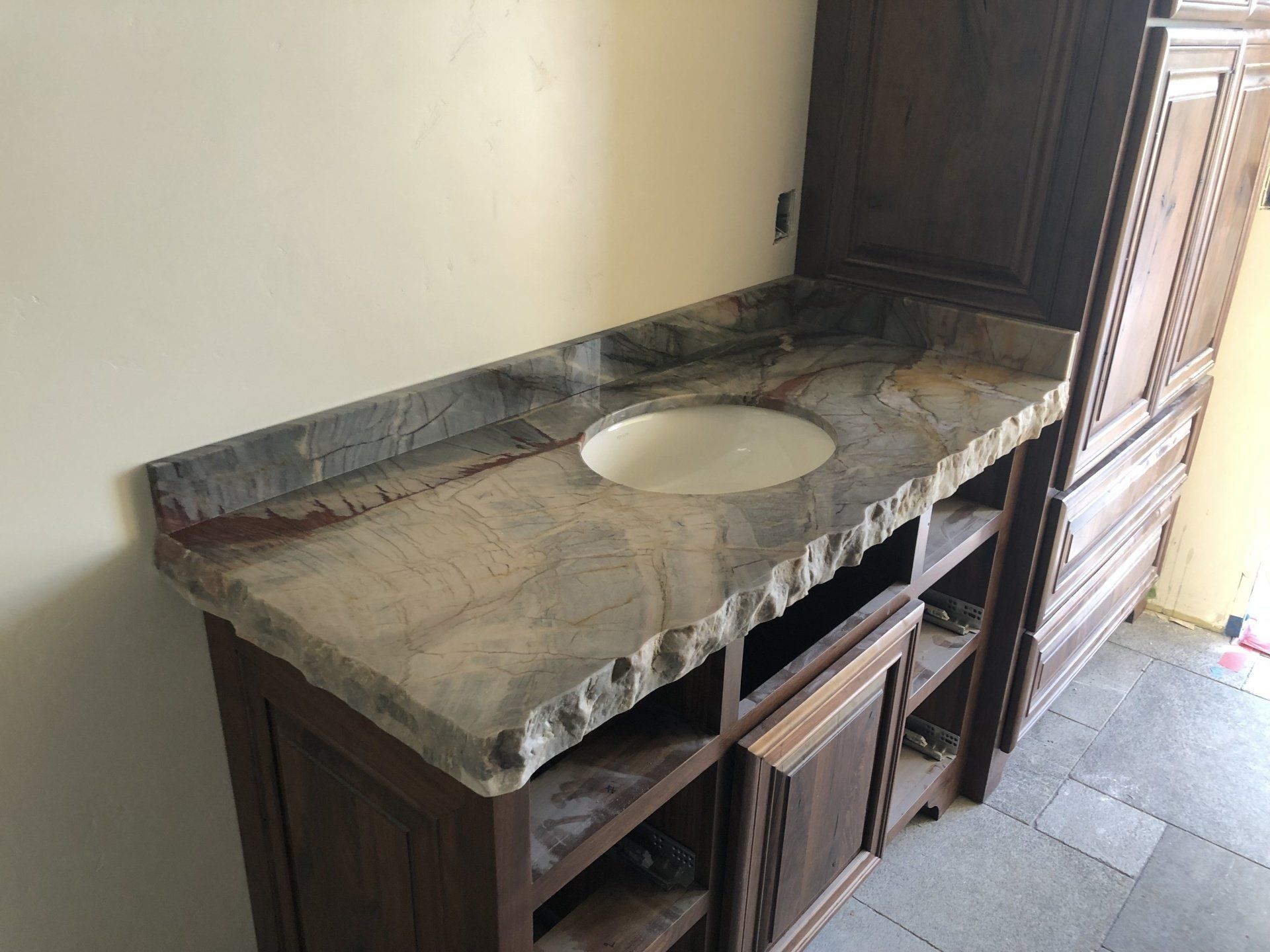 A bathroom vanity with a granite counter top and a sink