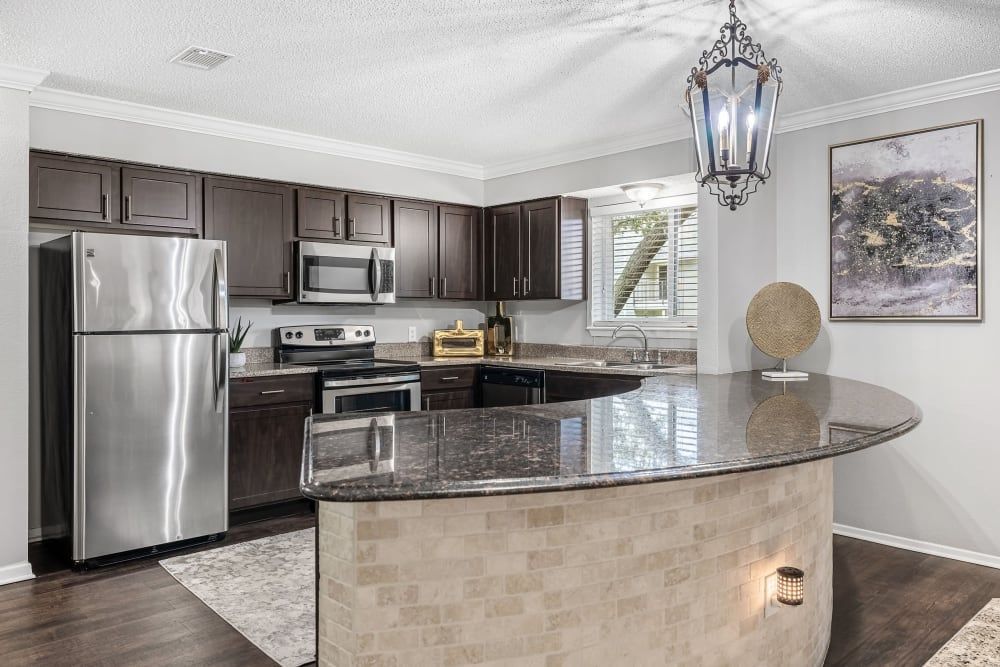 a kitchen with stainless steel appliances and granite counter tops at The Park at Flower Mound in Flower Mound, TX..