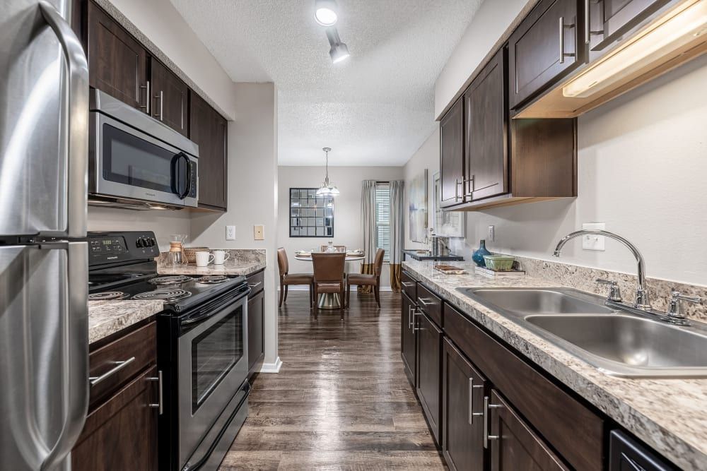 a kitchen with stainless steel appliances and granite counter tops at The Park at Flower Mound in Flower Mound, TX..
