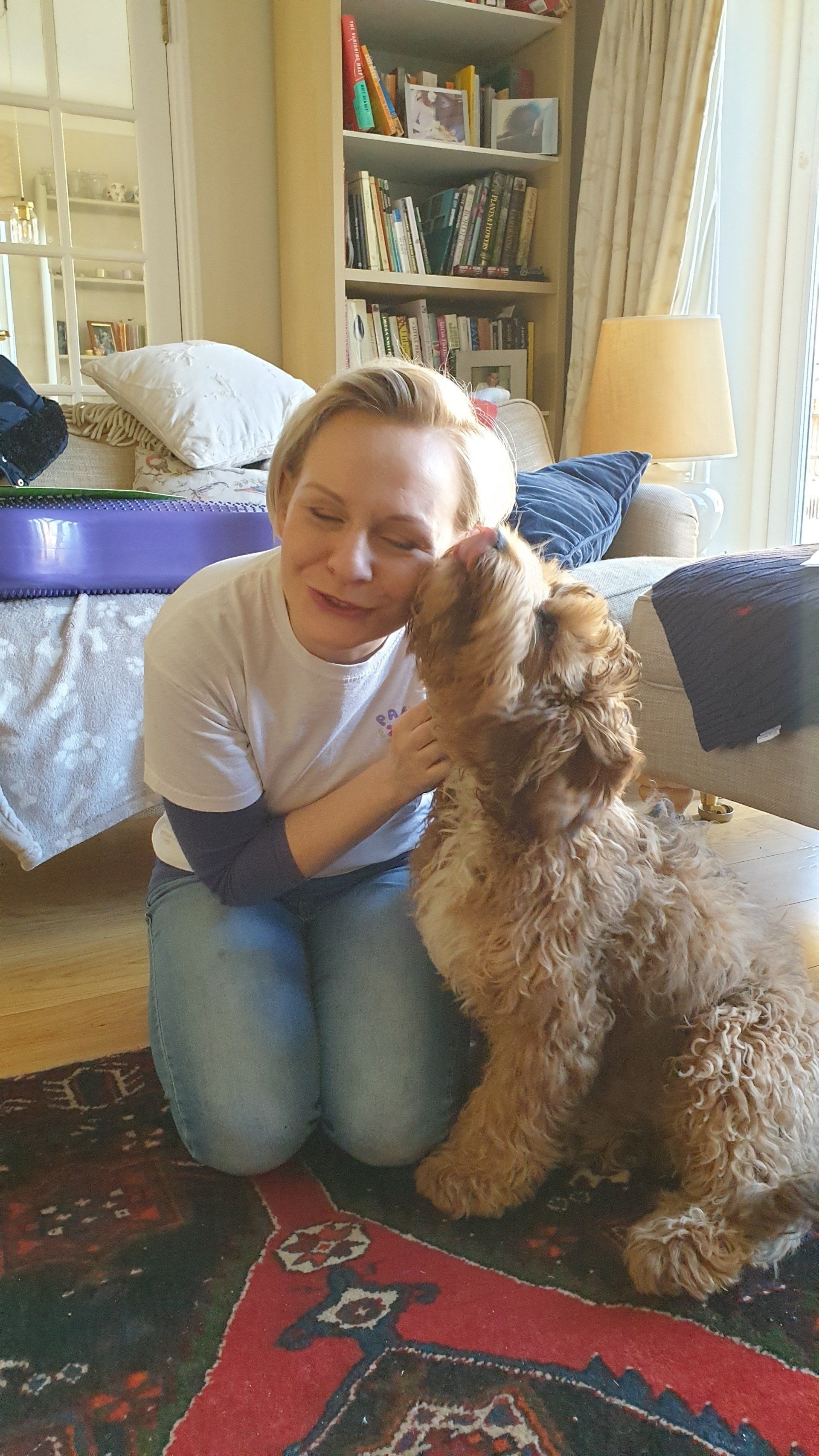 Very curly dog giving a middle-aged woman kisses.