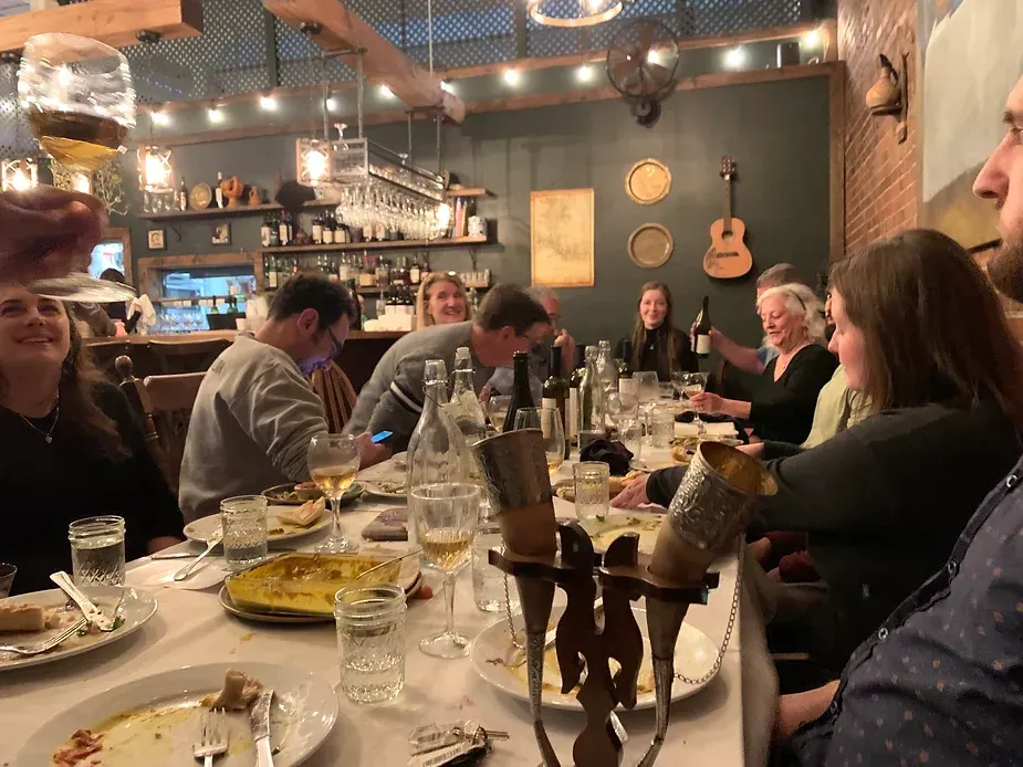 A group of people are sitting at a table with plates of food and glasses of wine.