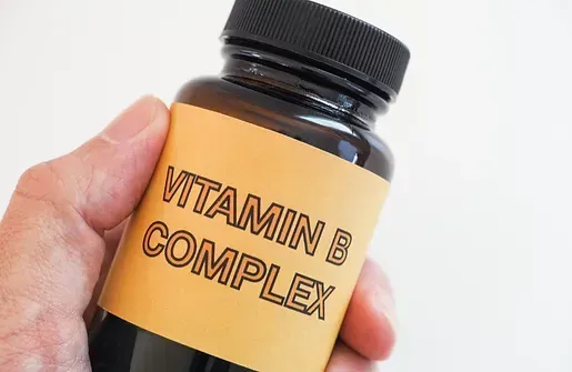 A person is holding a bottle of vitamin b complex.