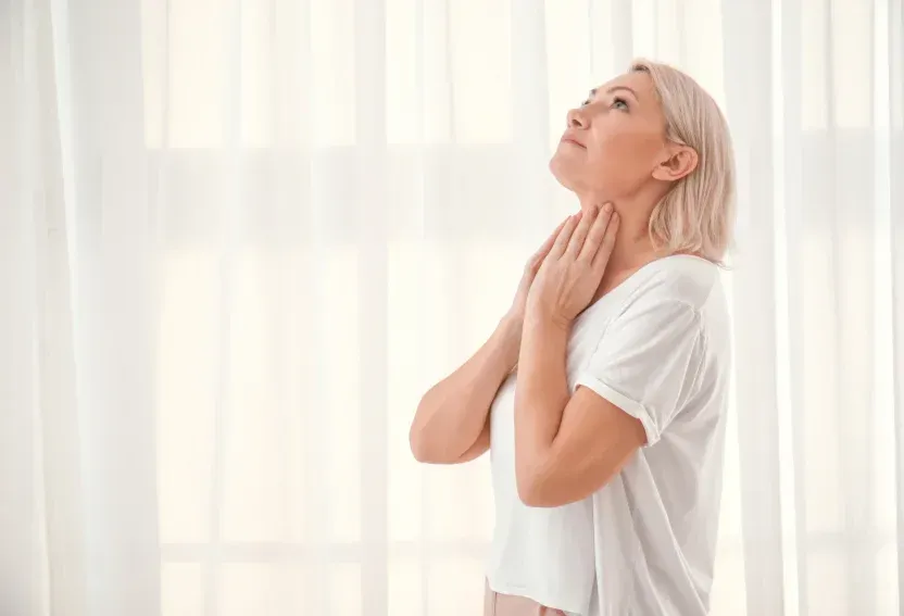 A woman is looking up at the sky while holding her neck.