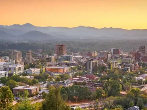 An aerial view of a city with mountains in the background at sunset.