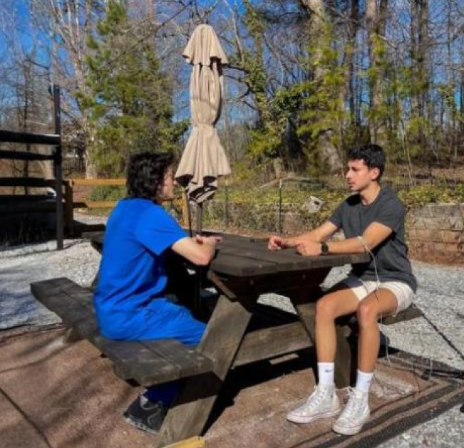 Two men are sitting at a picnic table talking to each other