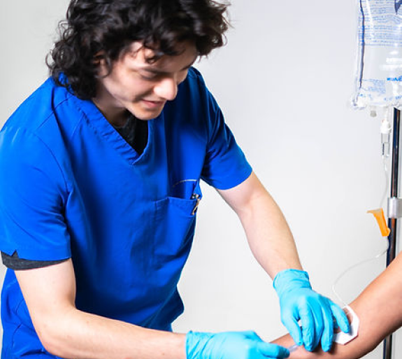 A man in a blue scrub is giving a patient an injection