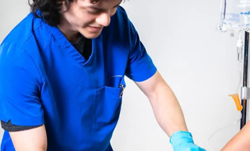 A nurse in a blue scrub is giving an injection to a patient.