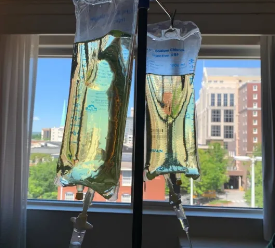 Two bags of liquid are hanging in front of a window