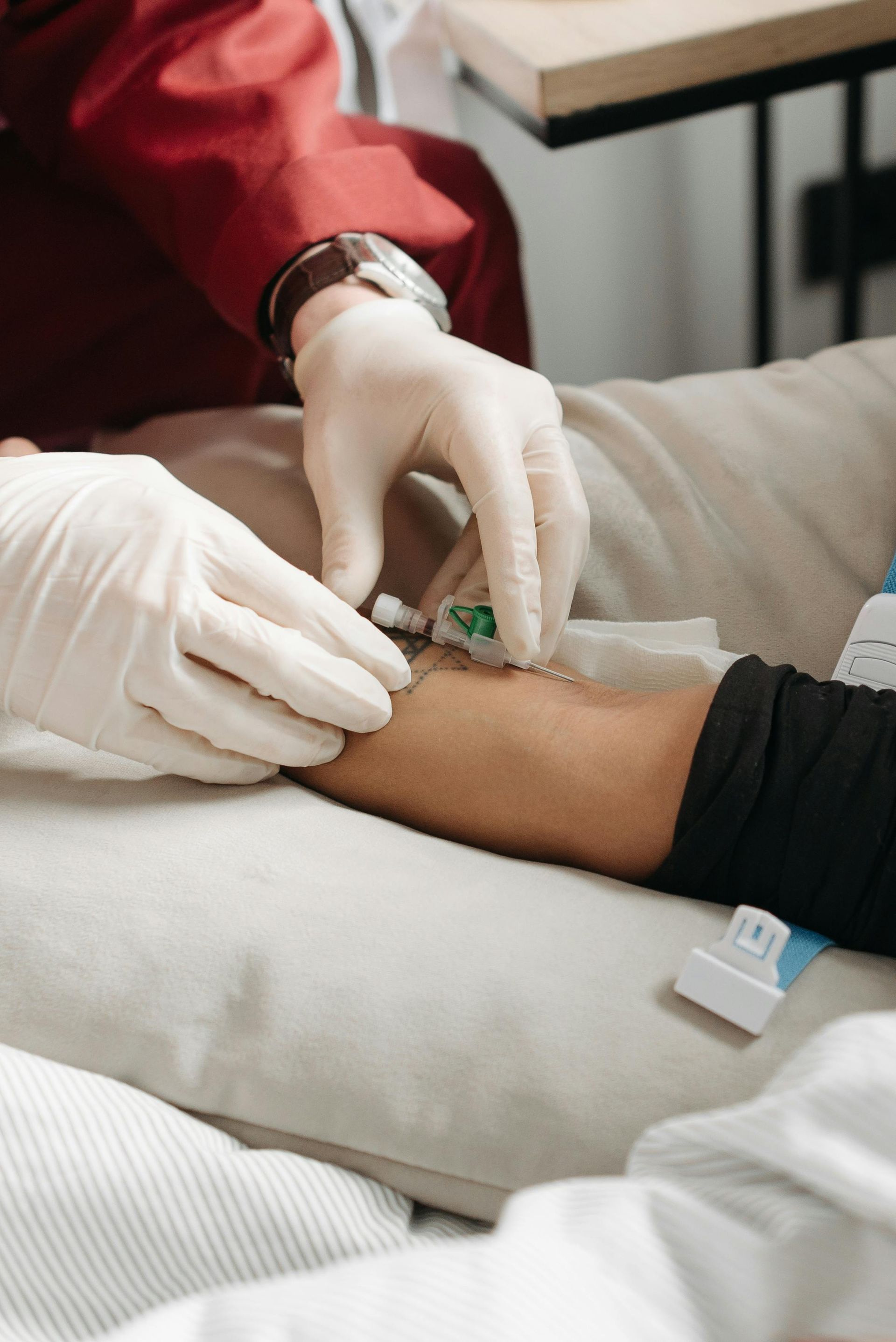 Person getting an IV inserted into their arm by a person wearing white gloves.