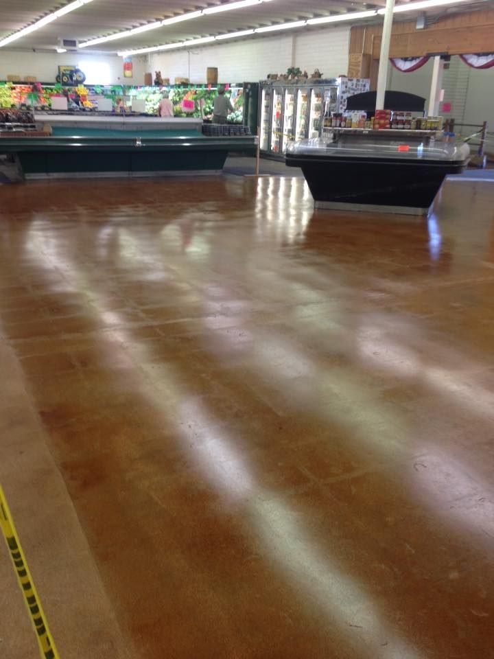 Polished brown grocery store floor with produce displays in background.