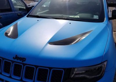 A blue jeep is parked in a parking lot.