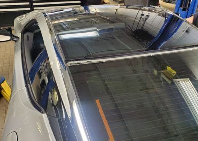 A white car with a black roof is parked in a garage.