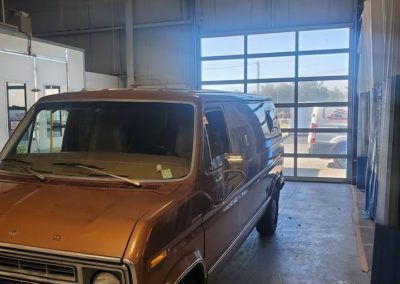 A brown van is parked in a garage next to a garage door.