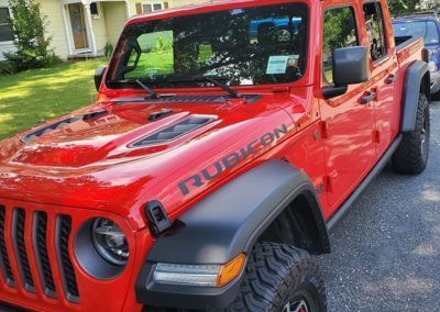 A red jeep is parked in a driveway in front of a house.