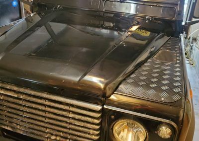 A black land rover defender is parked in a garage.