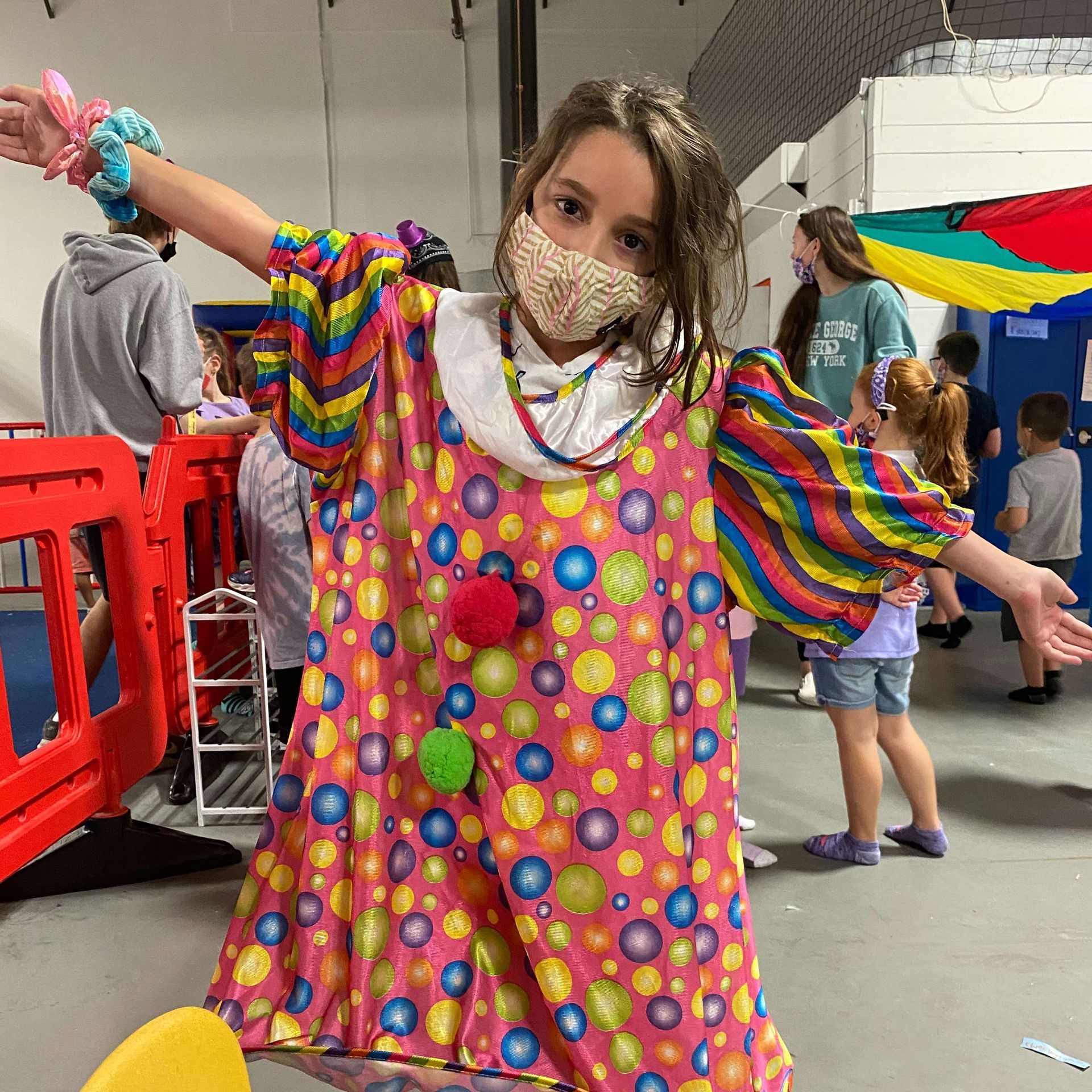 A young girl is wearing a clown costume and a mask.